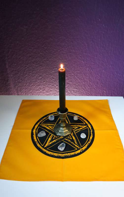 Altartuch in Gelb mit schwarzem Pentagramm in der Mitte mit brennender Kerze und Runen