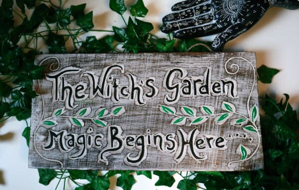 Handgefertigtes Holzschild The Witch's Garden mit Efeu und Handstatue als Deko