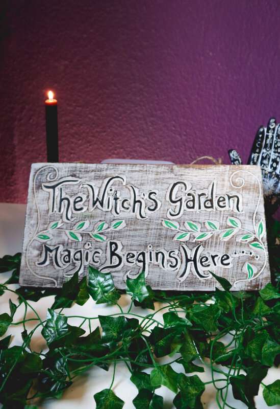 Handgefertigtes Holzschild The Witch's Garden mit Efeudeko und brennender Kerze