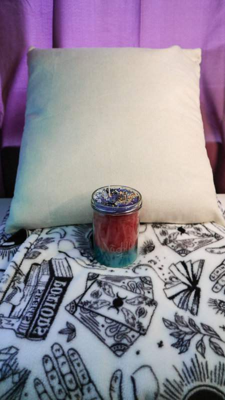 Ritualglaskerze Nächtlicher Frieden mit Bergkristall und Hämatit auf dem Bett mit Kopfkissen