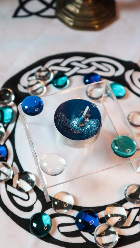 Blaue Teekerze Geistesblitz mit Glitzer auf durchsichtigem Podest mit Deko aus Glasperlen