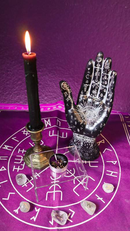 Teekerze Schutzgeist auf durchsichtigem Podest mit brennender Stabkerze und magische Handstatue als Deko
