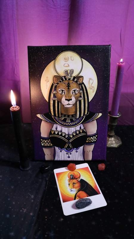 Leinwand Farbdruck ägyptische Göttin Sachmet auf Altar mit brennenden Kerzen mit Vergleichsbild und Heilsteinen als Deko und violettem Vorhand im Hintergrund