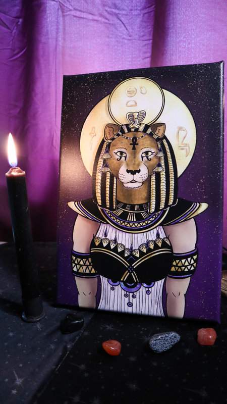 Leinwand Farbdruck ägyptische Göttin Sachmet auf Altar mit brennender Kerze und Heilsteinen als Deko und violettem Vorhand im Hintergrund