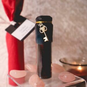 Spelljar Zuhause mit goldenem Schlüssel auf transparentem Podest mit Heilsteinen als Deko und brennendem Teelicht